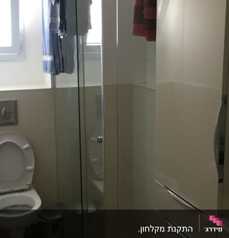 מקלחון זכוכית עם מגבות תלויות על מוט